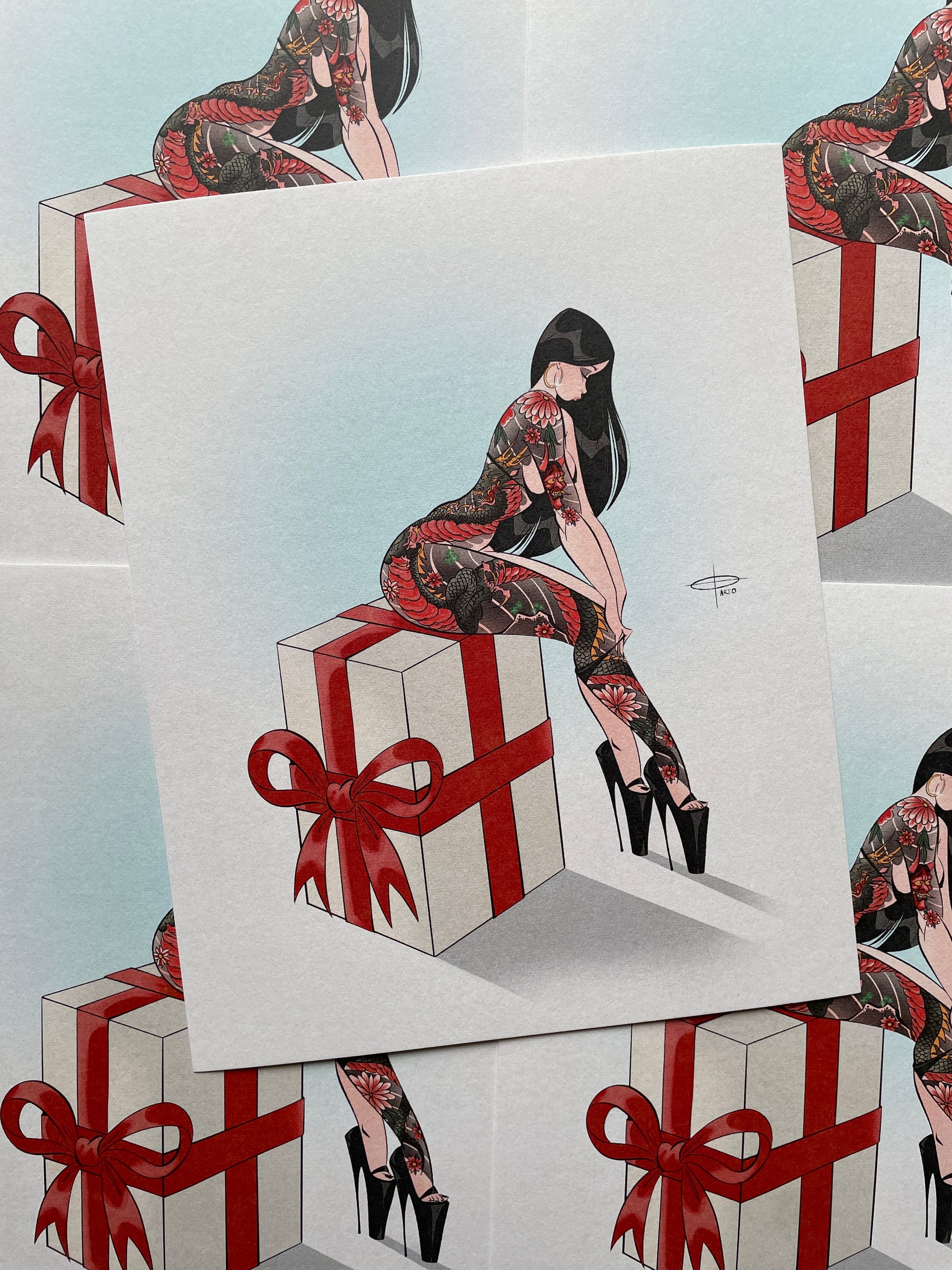 red ribbon print of tattooed woman sitting on present by bloodknotcollective